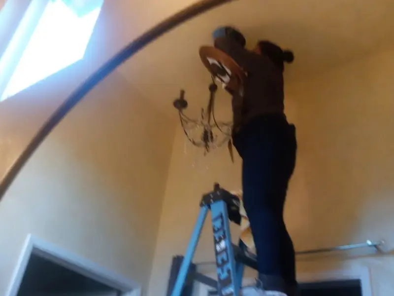 Electrician installing a chandelier in a Sorgho residence